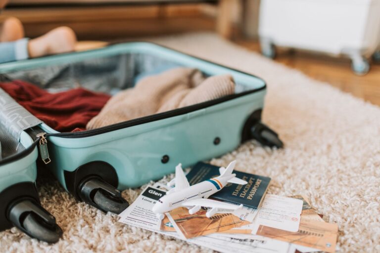 Open suitcase packed for travel with a passport, boarding pass and toy plane
