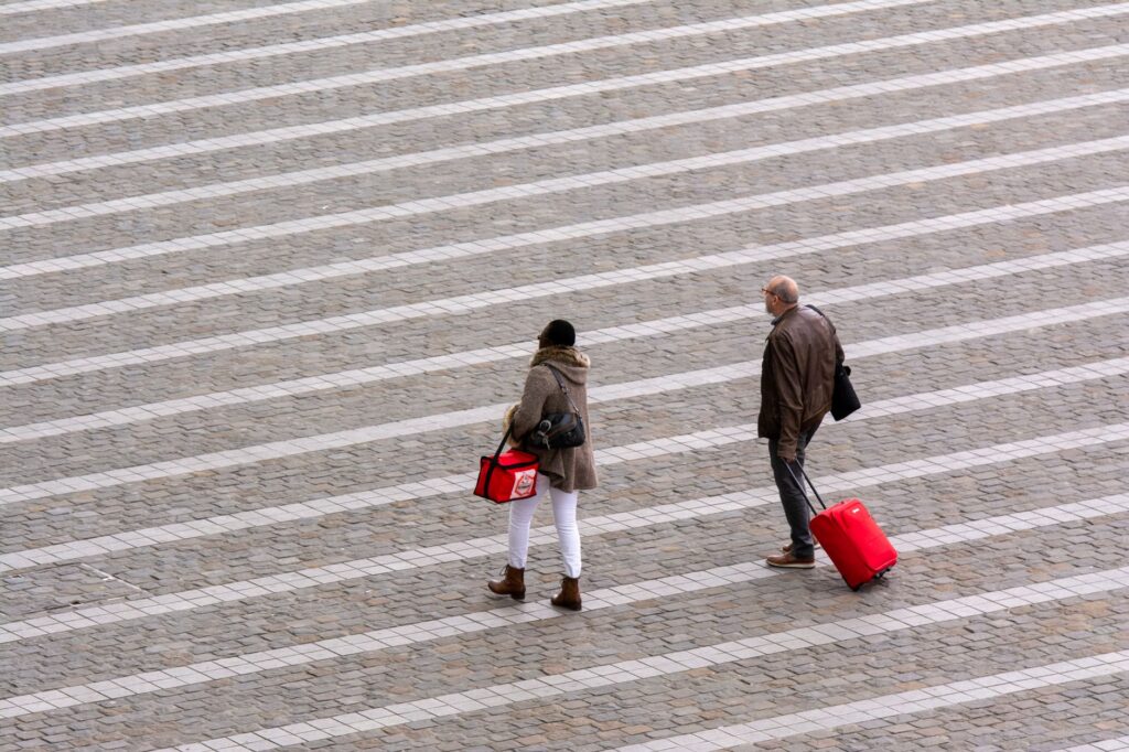 Aerial view of travelers walking with luggage, illustrating carry-on packing for a curling iron