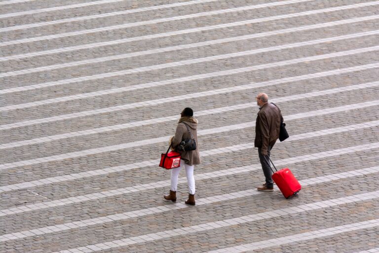 Aerial view of travelers walking with luggage, illustrating carry-on packing for a curling iron