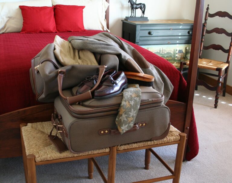 Carry-on luggage checklist: a packed carry-on suitcase and travel bag ready at the foot of a bed