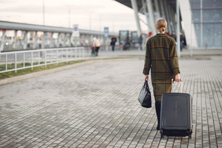 Traveler walking through an airport terminal with carry-on luggage before a security checkpoint