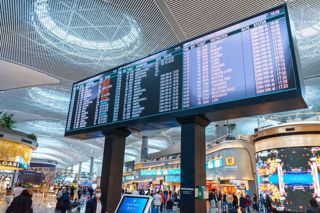 Passengers walk through Istanbul Airport's international departures area with flight information displays
