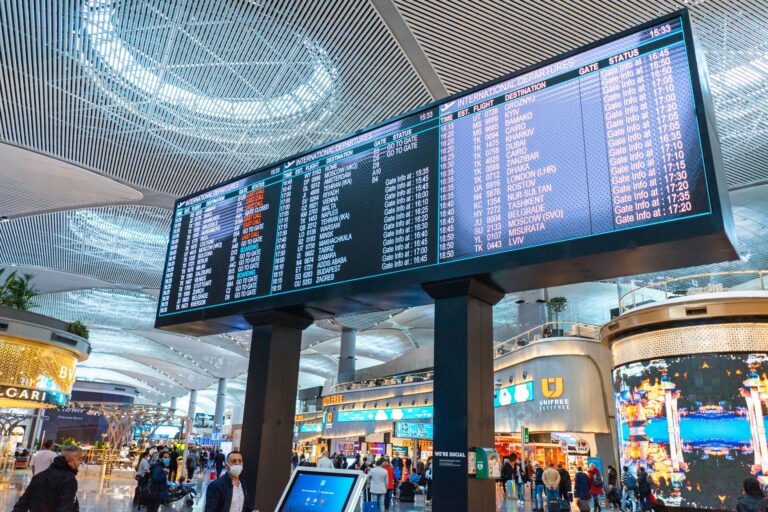 Passengers walk through Istanbul Airport's international departures area with flight information displays