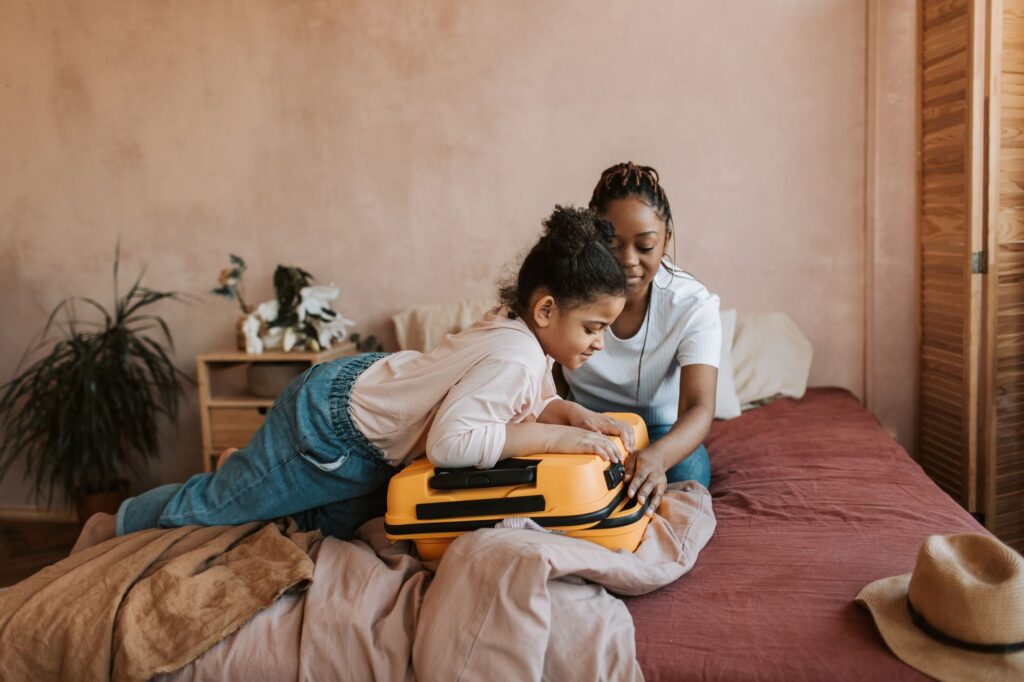 Mother and daughter packing a suitcase together before a trip requiring passport and travel documents