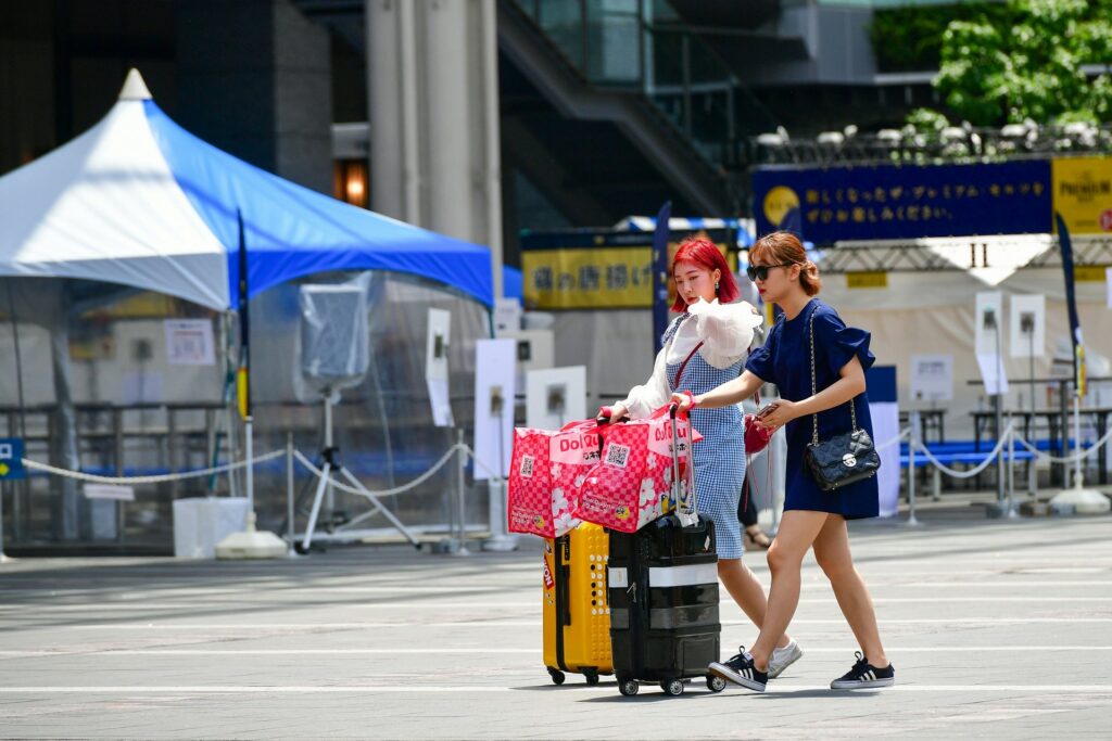 Two travellers walking across a city square pulling wheeled suitcases