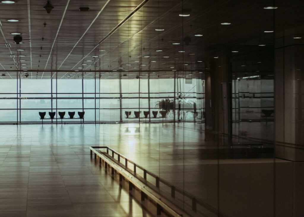 Empty airport terminal seating area with glass walls, near a security checkpoint