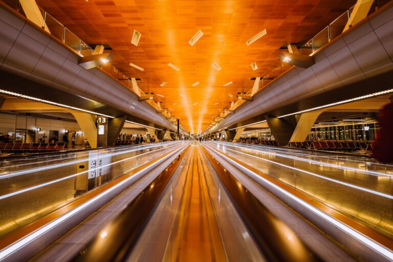 Dramatic long exposure of a modern airport terminal's moving walkalator with architectural ceiling design.