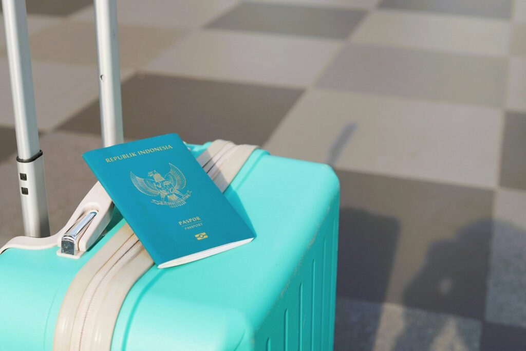 Passport resting on a turquoise carry-on suitcase at an airport
