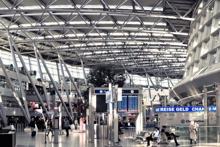 Modern airport departure terminal with information screens and travelers passing through the concourse