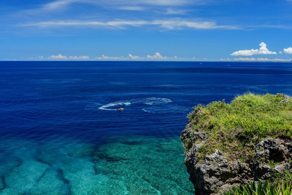 Turquoise reef water below a limestone cliff on the Okinawa coast, a reason to plan how many days in Okinawa