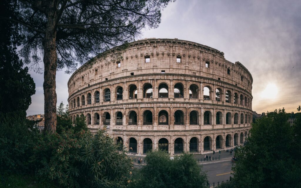 The Colosseum in Rome at sunset, framed by umbrella pines