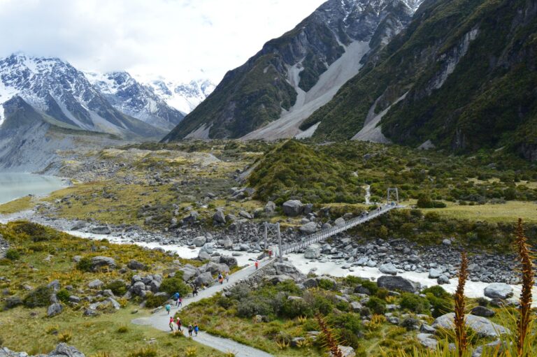 Walkers crossing a swing bridge on the Hooker Valley Track in Aoraki/Mount Cook National Park, New Zealand