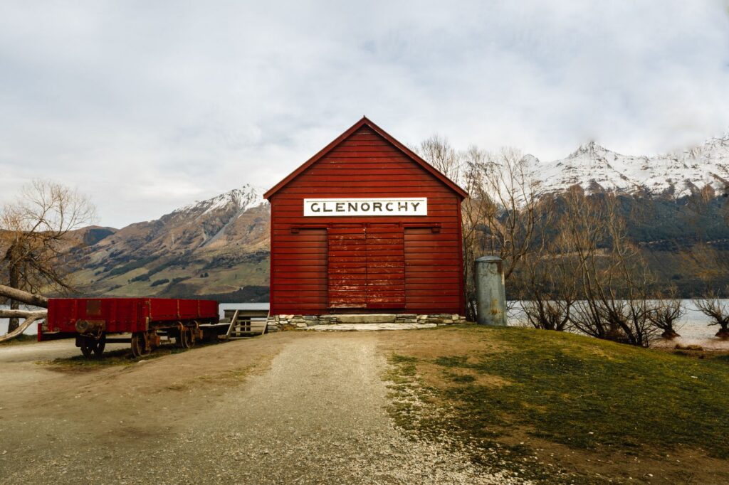 The red Glenorchy wharf shed with snow-capped mountains behind, day three of a Queenstown itinerary